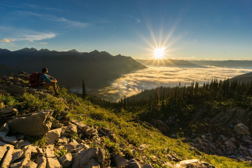 man sitting enjoying sunrise from mountain top