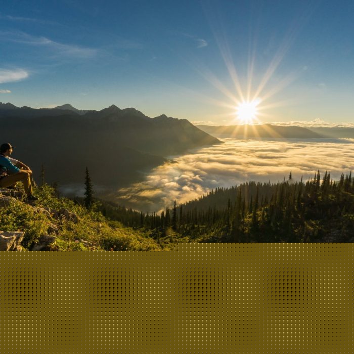 Hiker enjoying earlier morning sun along ridge top of Spineback Trail in Fernie BC